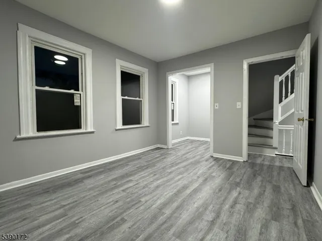a view of an empty room with wooden floor and windows