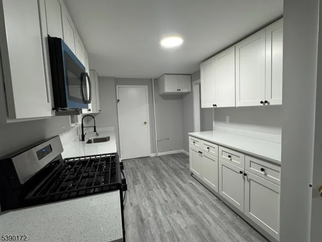 a kitchen with granite countertop a stove a sink dishwasher and cabinets with wooden floor