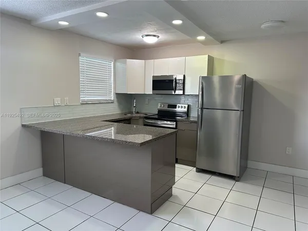 a kitchen with stainless steel appliances granite countertop a refrigerator sink a microwave and cabinets