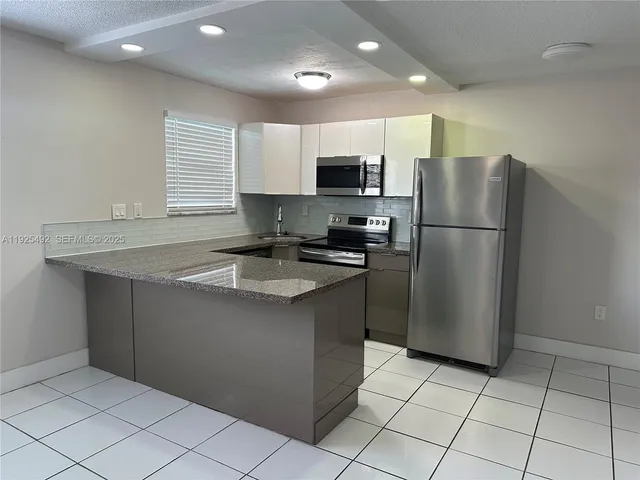 a kitchen with stainless steel appliances granite countertop a refrigerator sink a microwave and cabinets