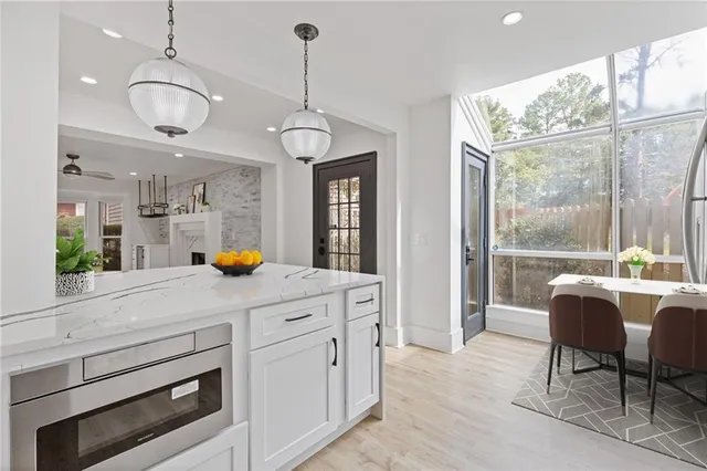 a kitchen with stainless steel appliances granite countertop a stove a sink a refrigerator a dining table and chairs with wooden floor