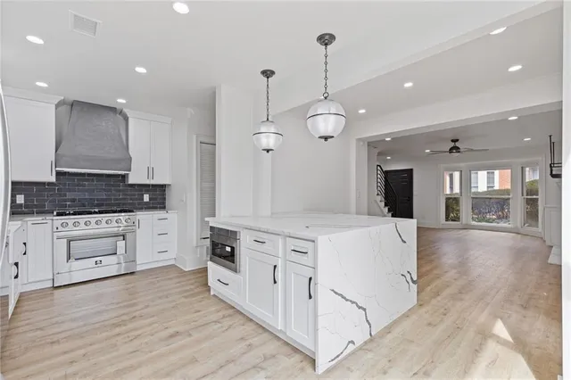 a large white kitchen with a white center island a stove a refrigerator and a fireplace