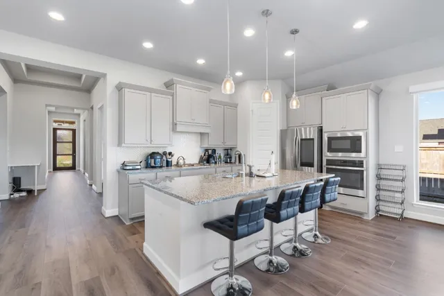 a large kitchen with kitchen island a dining table chairs and a refrigerator