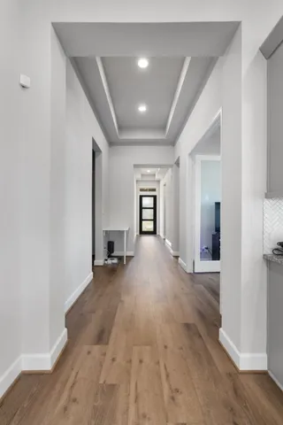 a view of a hallway with wooden floor and a bathroom