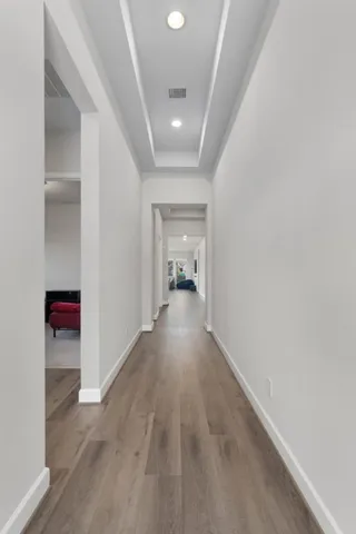 a view of a hallway with wooden floor and a bathroom