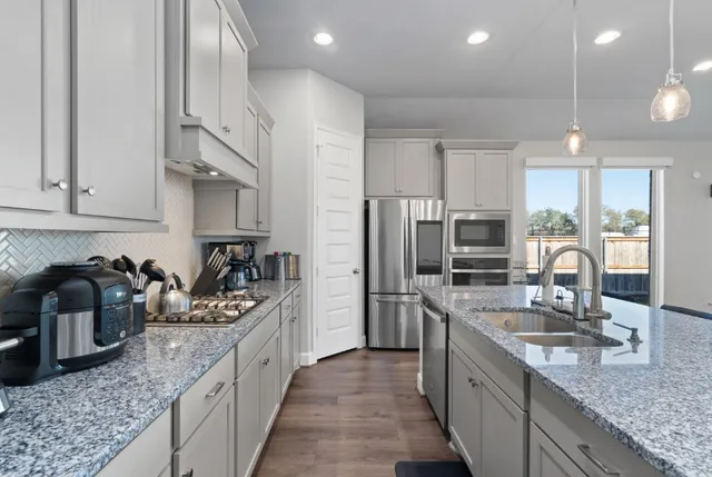 a large kitchen with stainless steel appliances granite countertop a sink stove and refrigerator