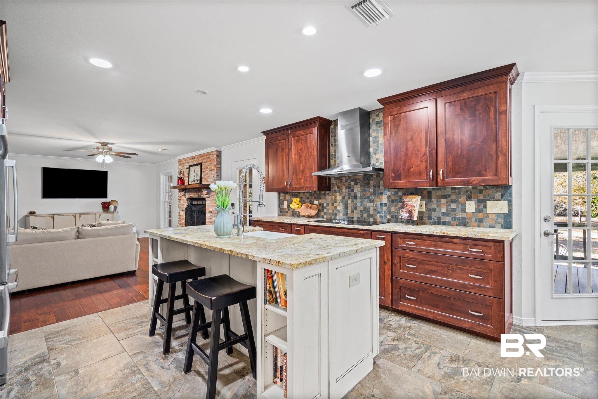 31369 Blakeley Way Daphne, AL 36527 - Photo 34 of 38 Two tone kitchen featuring two tone cabinetry, a kitchen breakfast bar, open floor plan, ornamental molding, and a brick fireplace