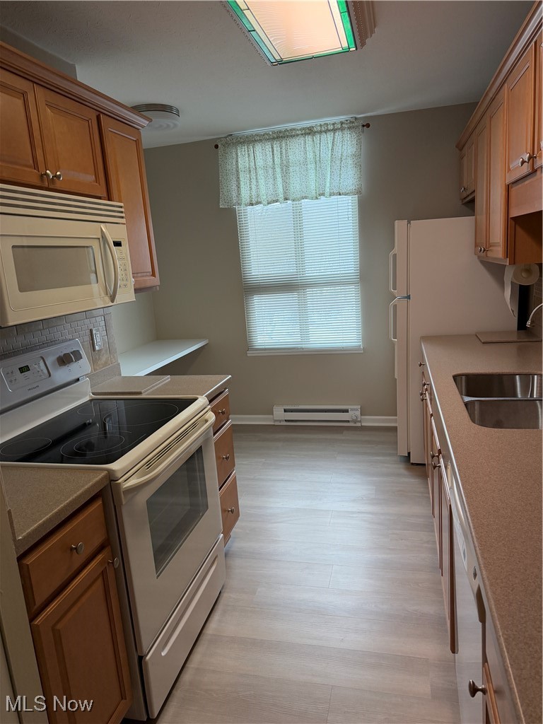 3066 Kent Road, Unit 407 Stow, OH 44224 - Photo 11 of 16 Kitchen featuring white range oven, a baseboard heating unit, light wood-type flooring, brown cabinets, and backsplash
