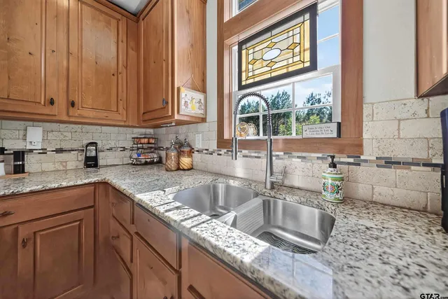 a kitchen with granite countertop a sink a counter top space cabinets and stainless steel appliances