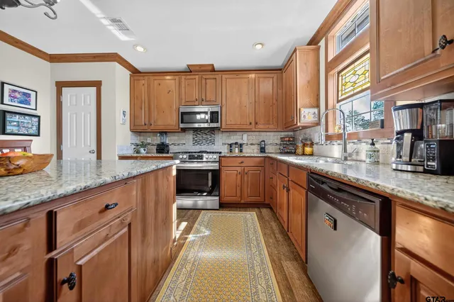 a kitchen with stainless steel appliances granite countertop wooden cabinets a sink and a stove