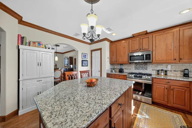 a kitchen with stainless steel appliances granite countertop a sink dishwasher stove top oven and cabinets with wooden floor