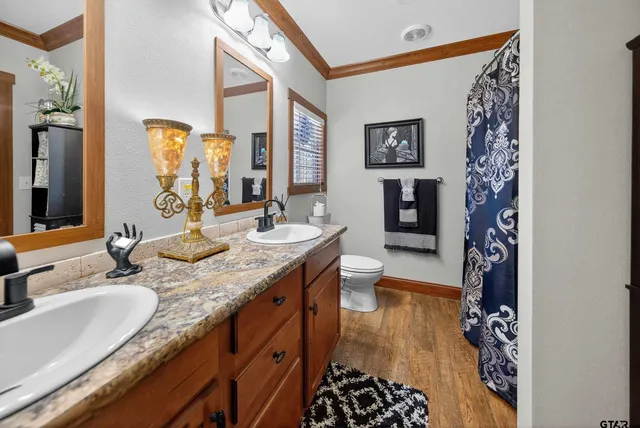 a bathroom with a granite countertop double vanity sink mirror and shower