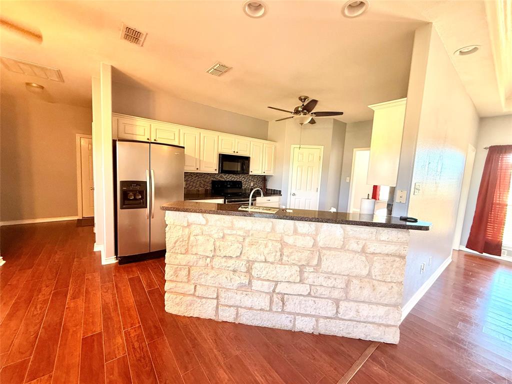 2429 Pecan Springs Road Cleburne, TX 76031 - Photo 11 of 21 a kitchen with stainless steel appliances kitchen island granite countertop a stove a sink and a refrigerator