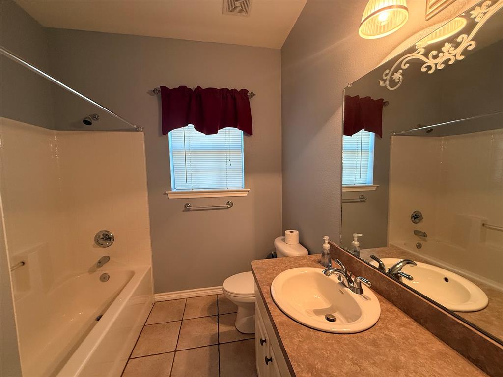 2429 Pecan Springs Road Cleburne, TX 76031 - Photo 7 of 21 a bathroom with a sink a toilet and mirror