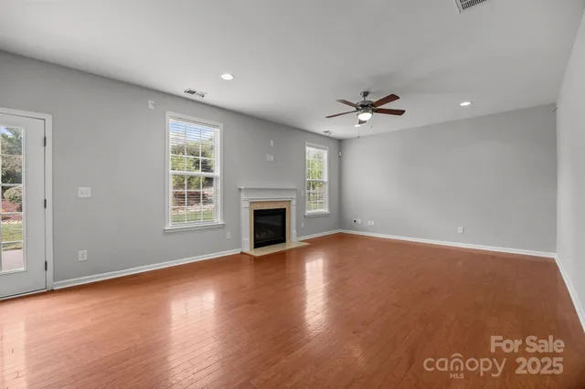 an empty room with fireplace fan and windows