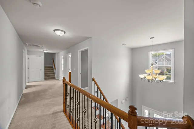 a view of a hallway to a bedroom with wooden floor and chandelier