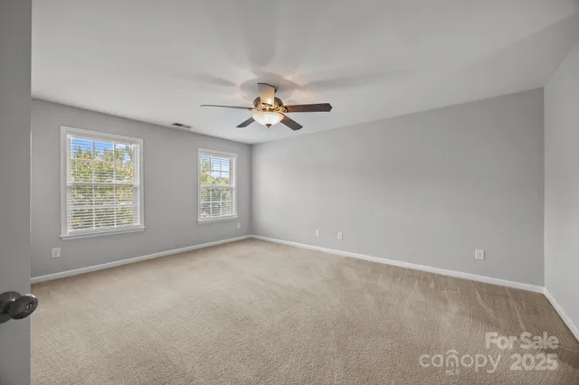 an empty room with windows and fan