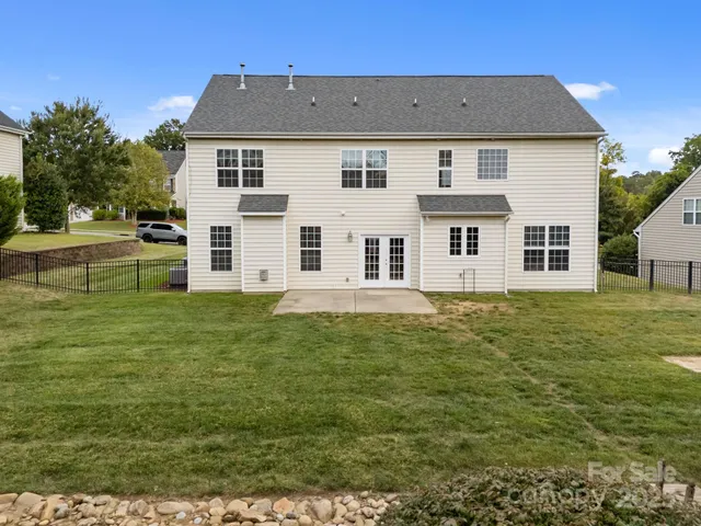 a view of a yard in front of a house with plants and large tree