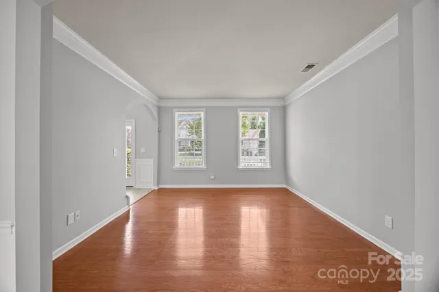 a view of an empty room with wooden floor and window