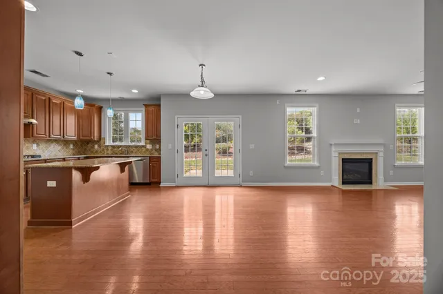 a large kitchen with stainless steel appliances granite countertop a stove top oven a sink dishwasher a dining table and chairs with wooden floor