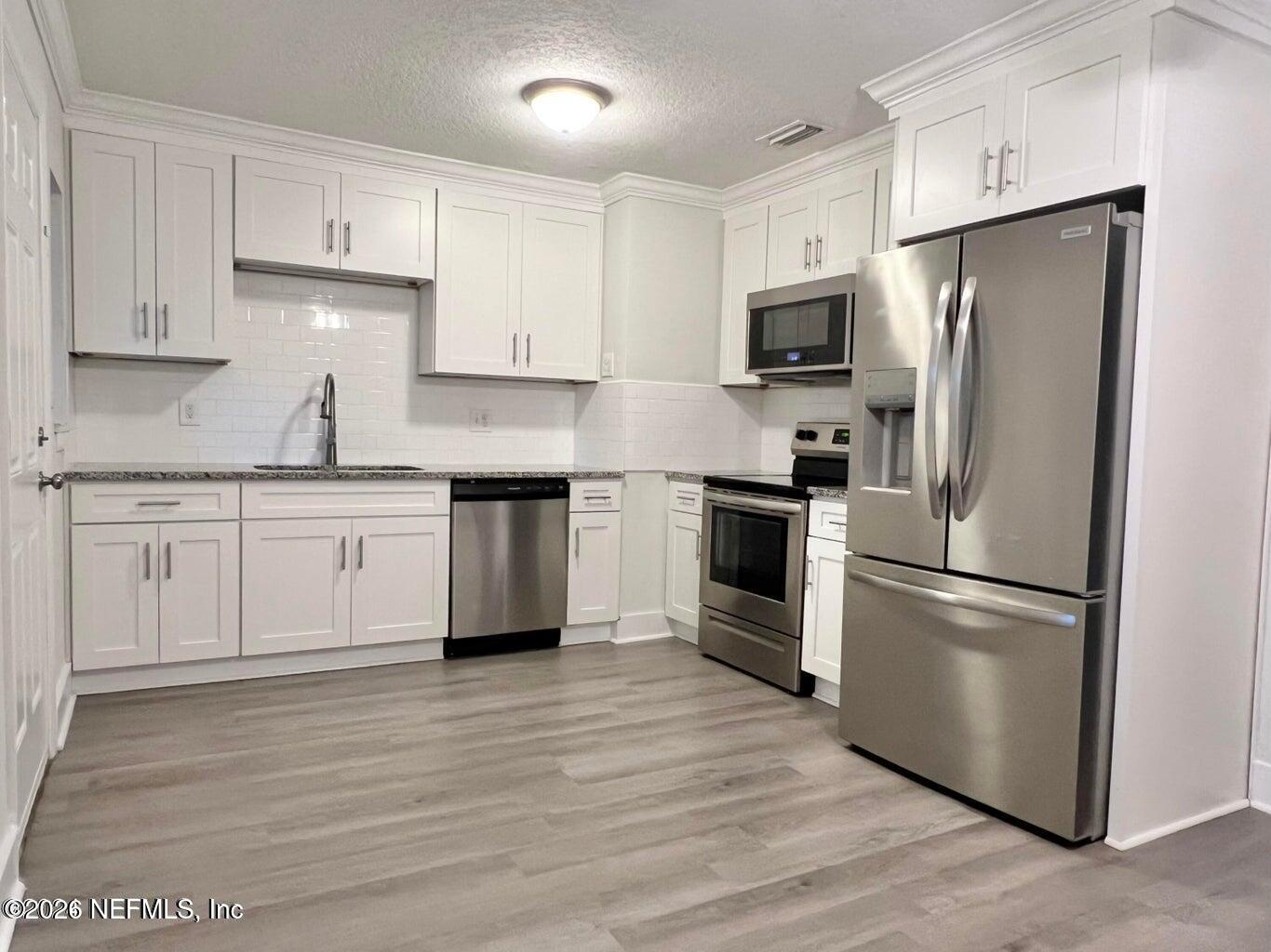 1961 New Haven Road Jacksonville, FL 32211 - Photo 28 of 53 a kitchen with stainless steel appliances granite countertop a refrigerator stove a sink and white cabinets