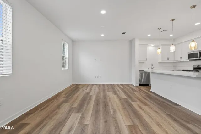 a kitchen with stainless steel appliances granite countertop a sink a stove a refrigerator and white cabinets