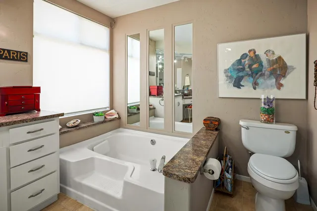a bathroom with a granite countertop toilet sink and mirror