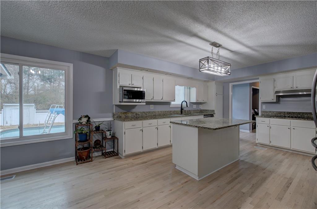 16 High Point Drive Southwest Cartersville, GA 30120 - Photo 13 of 44 a kitchen with stainless steel appliances granite countertop a stove top oven a sink dishwasher and white cabinets with wooden floor