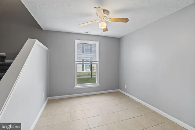 an empty room with windows and ceiling fan