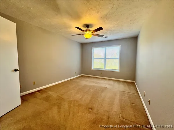 an empty room with windows and fan