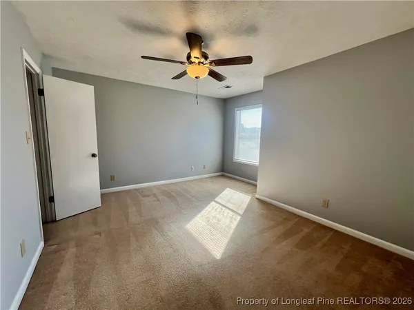 an empty room with windows and fan