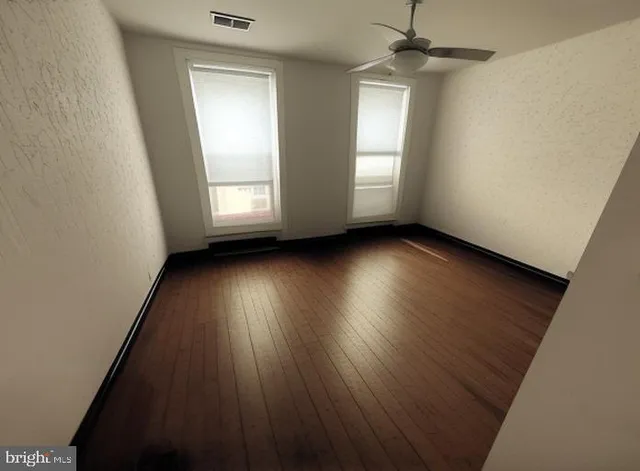 an empty room with wooden floor and windows