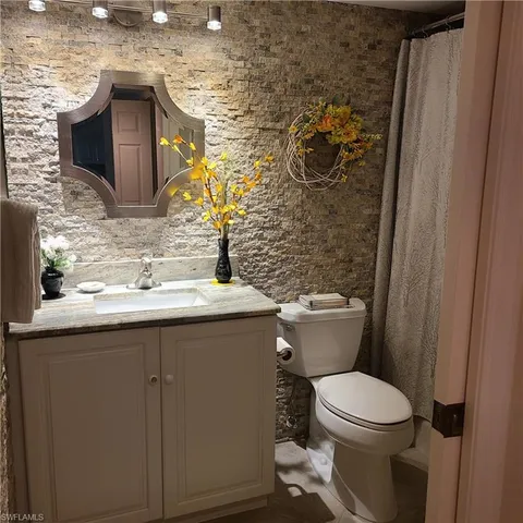 a bathroom with a granite countertop toilet sink and mirror