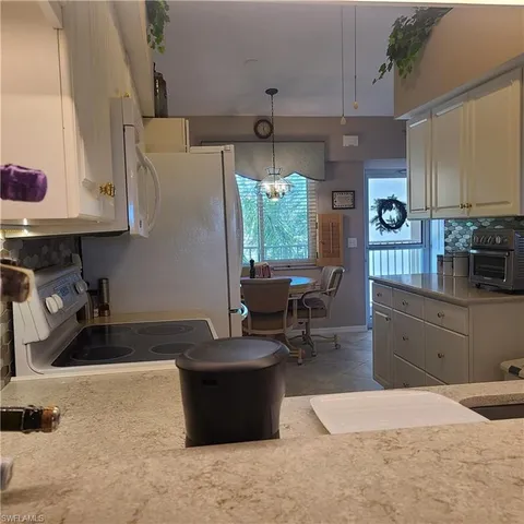 a kitchen with granite countertop a stove a sink a refrigerator and wooden cabinets