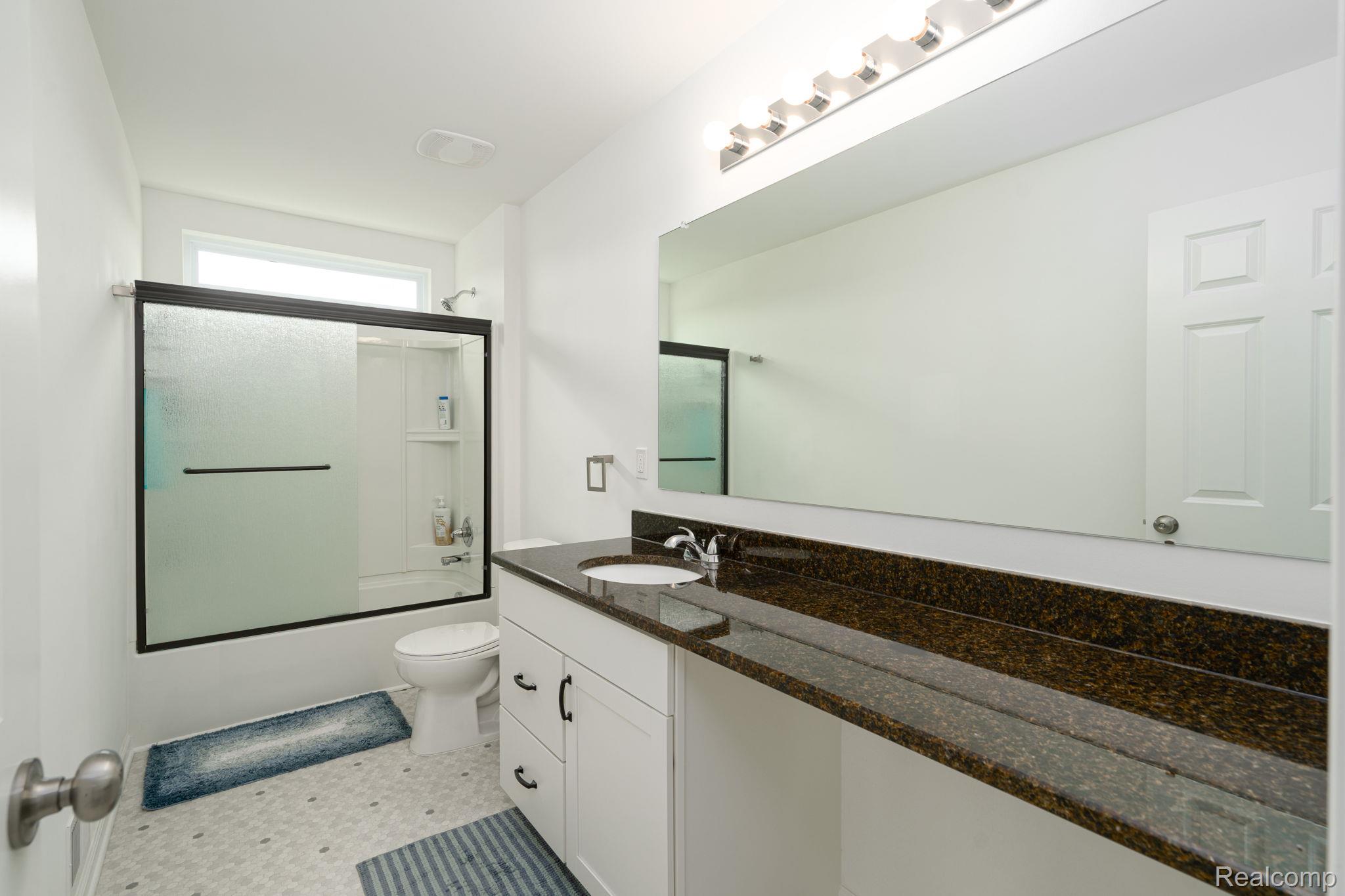 48904 Carnegie Way Macomb, MI 48042 - Photo 29 of 34 Bathroom featuring a spacious vanity with integrated sink, dark speckled countertop, and white cabinetry