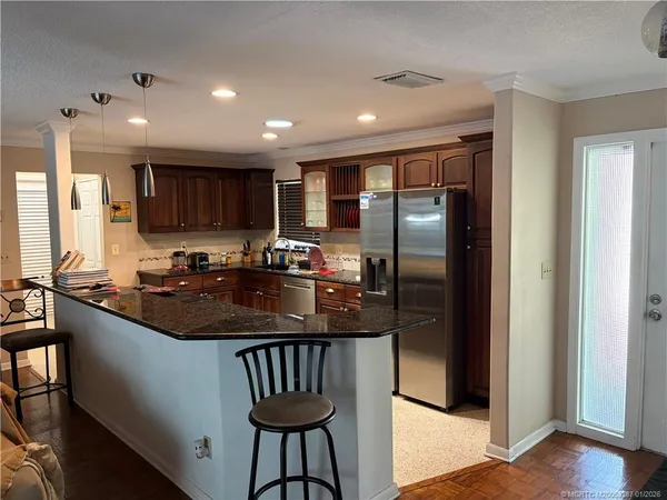 a kitchen with kitchen island granite countertop a sink a stove a refrigerator cabinets and a dining table