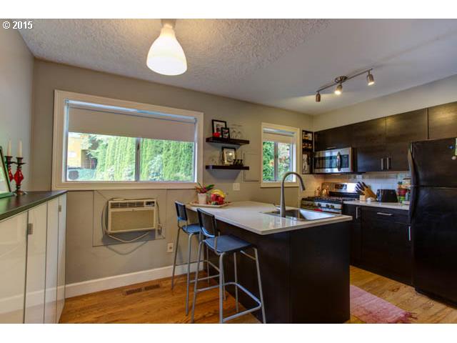 839 Southwest Broadway Drive, Unit 71 Portland, OR 97201 - Photo 7 of 15 a kitchen with stainless steel appliances granite countertop a sink a stove a refrigerator a dining table and chairs with wooden floor