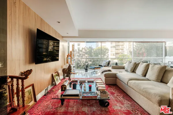 a living room with furniture a flat screen tv and a floor to ceiling window