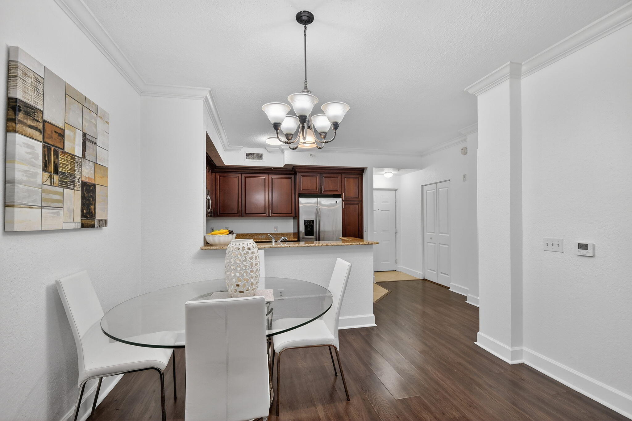 3110 Renaissance Way, Unit 110 Boynton Beach, FL 33426 - Photo 10 of 45 a dining room with wooden floor a chandelier a glass table and chairs