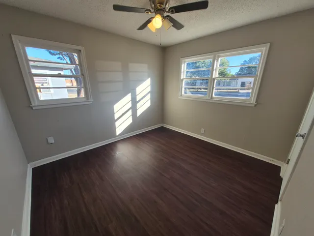 an empty room with wooden floor and window