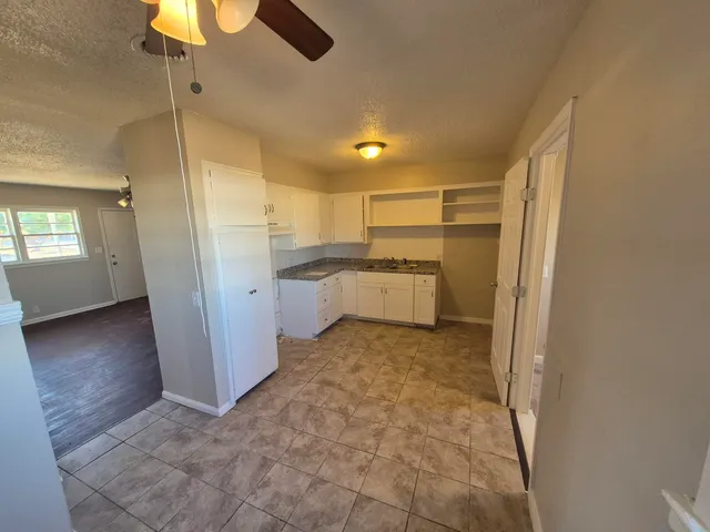a kitchen with granite countertop white cabinets and white appliances