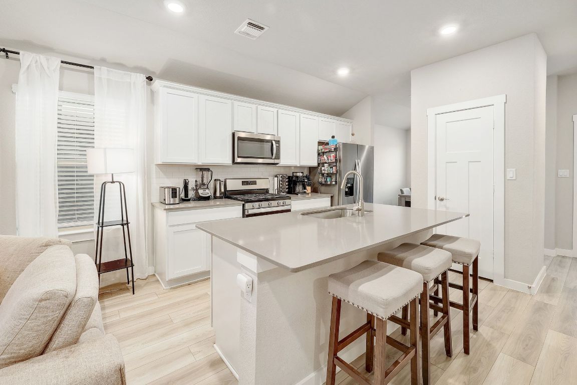 204 Halford Road Georgetown, TX 78633 - Photo 7 of 27 a kitchen with kitchen island granite countertop a stove a sink a microwave a dining table and chairs