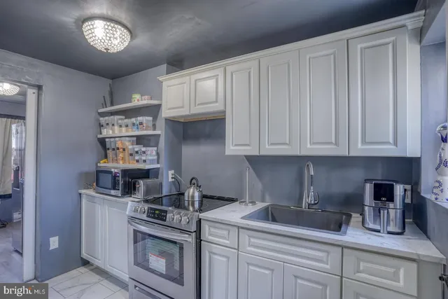 a kitchen with stainless steel appliances granite countertop a stove a sink and a white cabinets