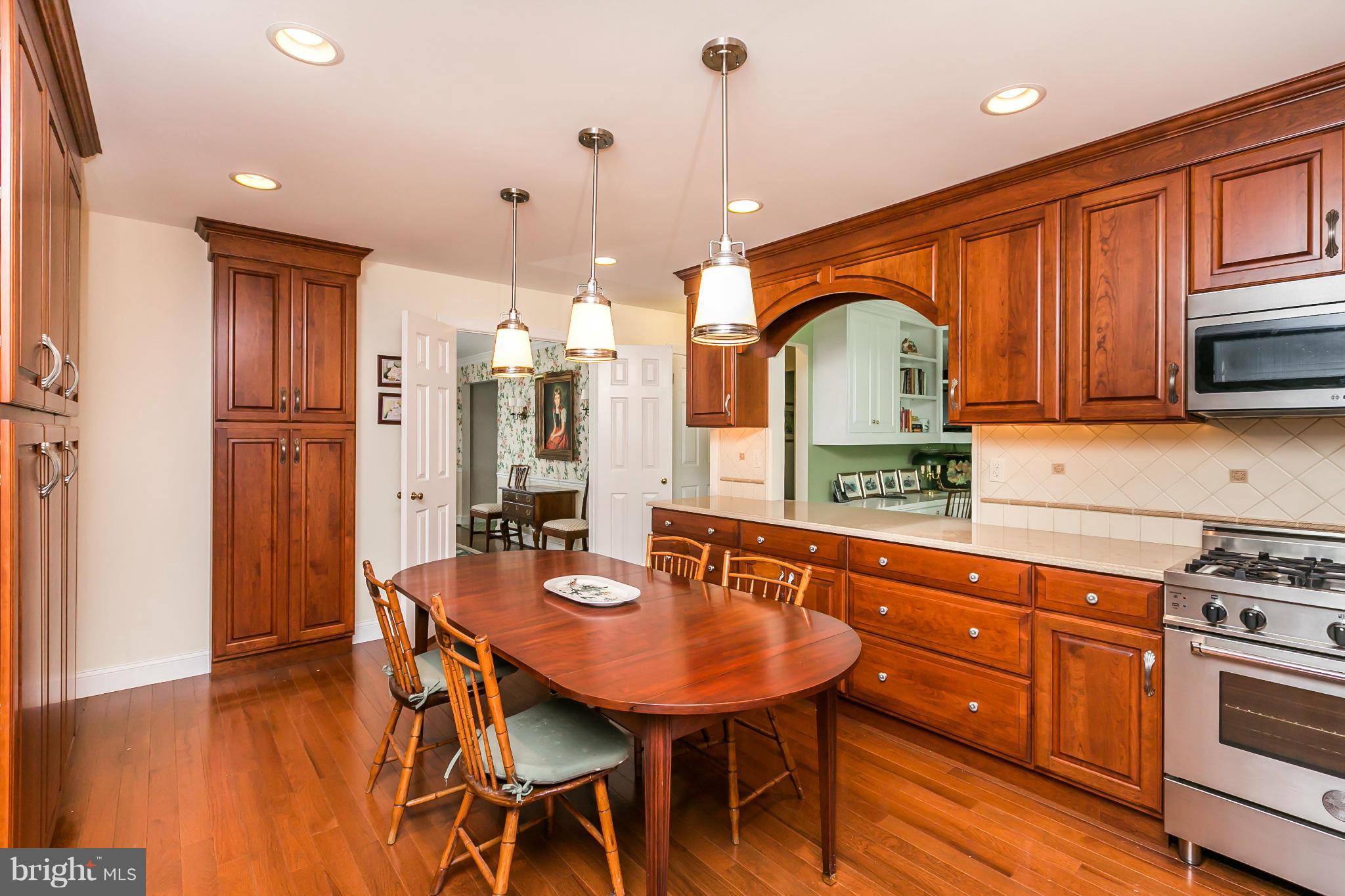 109 Charlesbrooke Road Baltimore, MD 21212 - Photo 12 of 30 a kitchen with stainless steel appliances granite countertop a kitchen island a stove a table and chairs with wooden floor