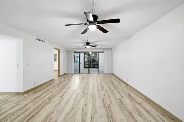 a view of empty room with wooden floor and ceiling fan