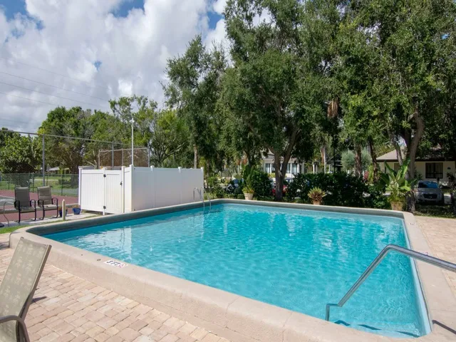 a view of swimming pool with seating area and trees in the background