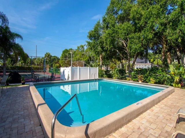 a view of swimming pool with seating area and trees in the background