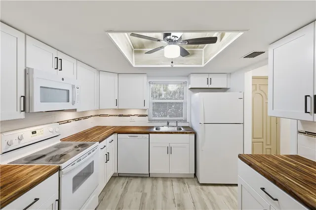 a kitchen with a sink a refrigerator a stove and white cabinets