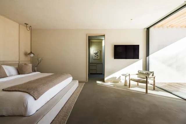 a spacious bedroom with a bed and a flat screen tv