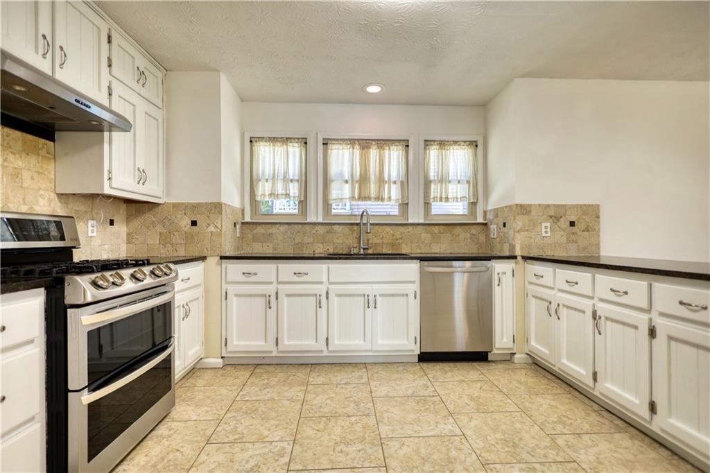5113 Brownlee Road Southwest Lilburn, GA 30047 - Photo 13 of 48 a kitchen with granite countertop white cabinets stainless steel appliances a sink and a window